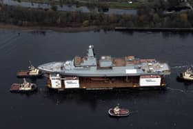 HMS Glasgow, the first of the new Type 26 frigates, sailing on a submergible barge being towed down the Clyde on her way to Geln Mallan on Loch Long. Picture: John Devlin.