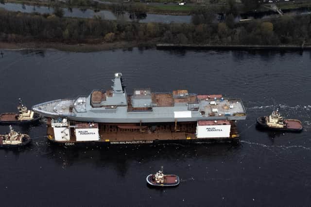 HMS Glasgow, the first of the new Type 26 frigates, sailing on a submergible barge being towed down the Clyde on her way to Geln Mallan on Loch Long. Picture: John Devlin.