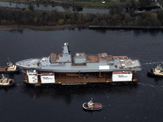 HMS Glasgow, the first of the new Type 26 frigates, sailing on a submergible barge being towed down the Clyde on her way to Geln Mallan on Loch Long. Picture: John Devlin.