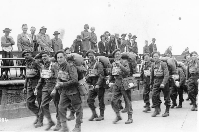 British or Canadian troops walk along the Southsea seafront, about to embark at South Parade Pier. The civilians would not have been allowed to be present before D-Day.