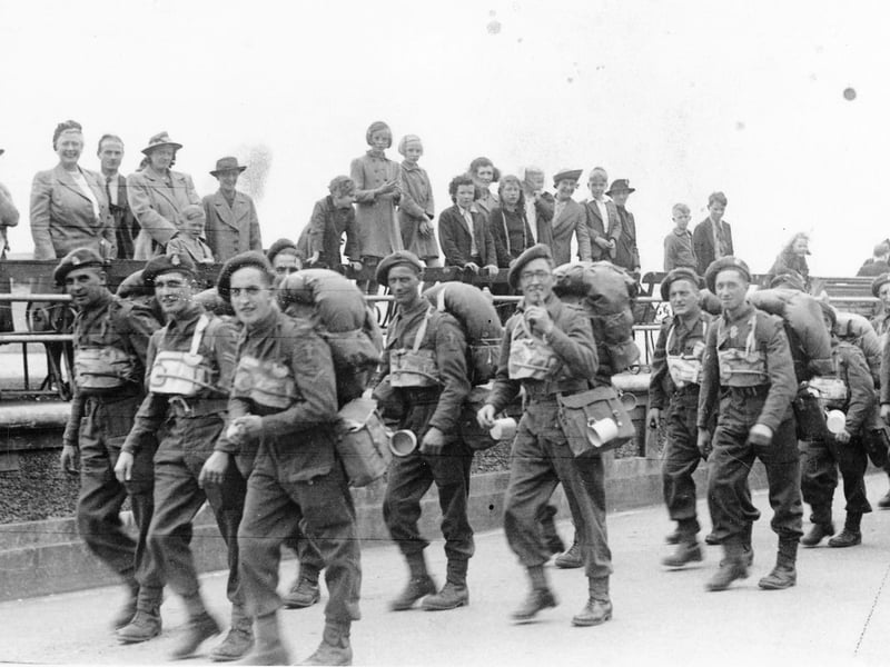 British or Canadian troops walk along the Southsea seafront, about to embark at South Parade Pier. The civilians would not have been allowed to be present before D-Day.