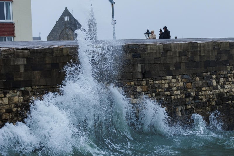 A moody sea crashed waves high onto footpaths as passer-by's did their best to get out the way