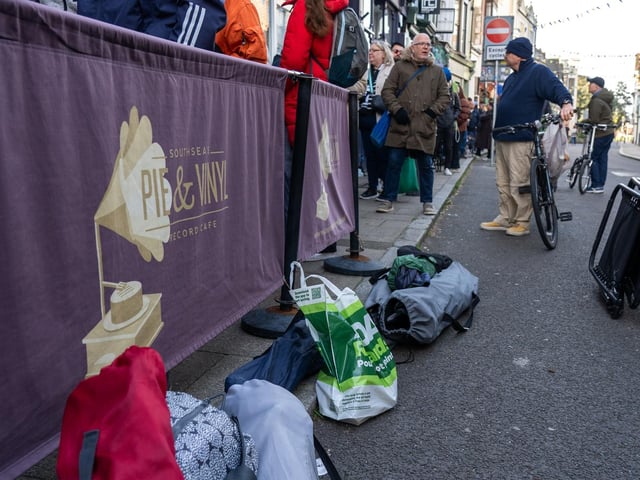 A group of people queuing outside Pie and Vinyl with tents