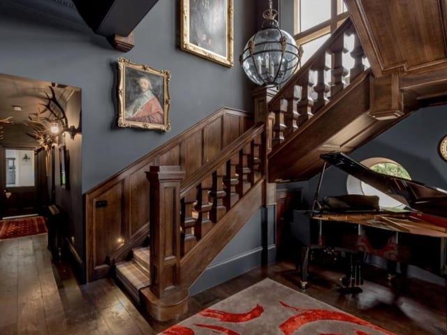 The hallway features a wooden staircase up to the first floor and a Jacobean mullioned window above, boasting a rich wooden design.
