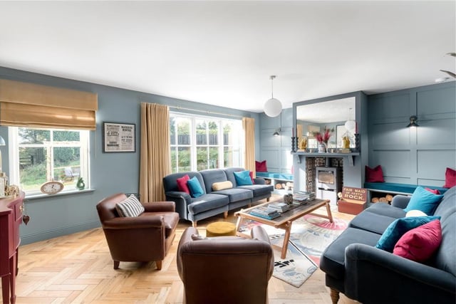 The sitting room sits across the hall from the kitchen/dining room, and has feature panelled walls, a wood burning stove, beautiful solid wood parquet flooring and windows overlooking the garden.