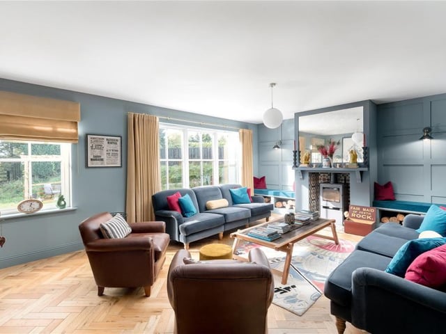 The sitting room sits across the hall from the kitchen/dining room, and has feature panelled walls, a wood burning stove, beautiful solid wood parquet flooring and windows overlooking the garden.