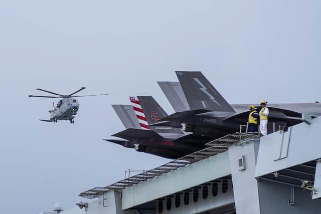 Flight Deck staff stand next to the F35 planes aboard HMS Queen Elizabeth at HM Naval Base, Portsmouth, ahead of the ship's maiden deployment to lead the UK Carrier Strike Group on a 28-week operational deployment travelling over 26,000 nautical miles from the Mediterranean to the Philippine Sea. Picture date: Saturday May 22, 2021.