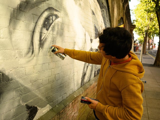 Pictured is: Abraham O at work on his mural, one of many artworks along the railway arches by the Hard.  Picture: Keith Woodland (140921-112)