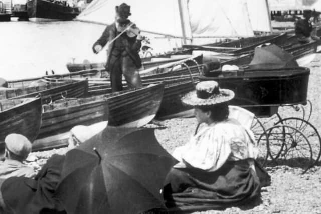 A busker playing his violin on the beach near Clarence Pier, Southsea, about 1895.