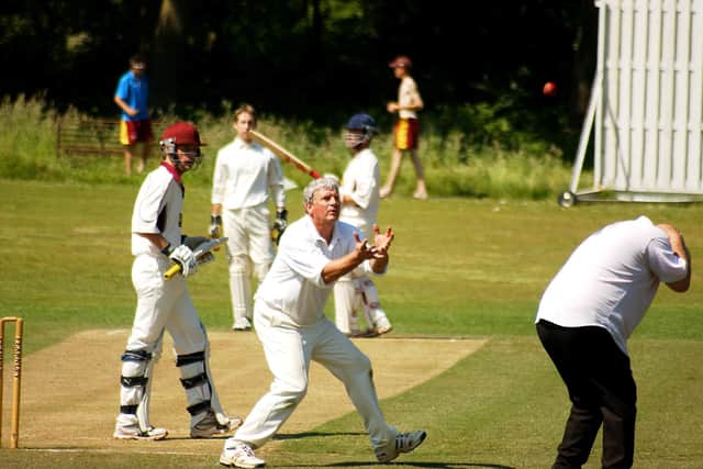 The umpires takes cover as Jim Smallbone prepares to receive the ball during his long career with Petersfield.