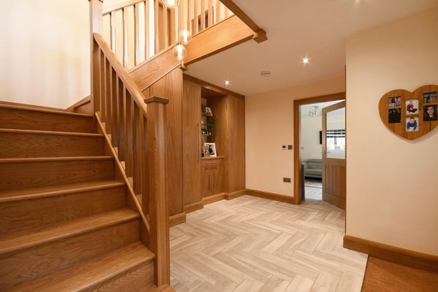The entrance hallway has tiled flooring in a herringbone style, benefiting from under-tile heating that runs throughout the open-plan ground floor living space. There is a "beautiful, imposing" solid oak staircase, built-in oak finished storage cupboards and a downstairs W/C.