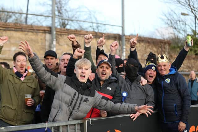 Hawks boss Paul Doswell, far right, with a king crown placed on his head, enjoys the Dulwich Hamlet win with some of the away following Picture: Dave Haines