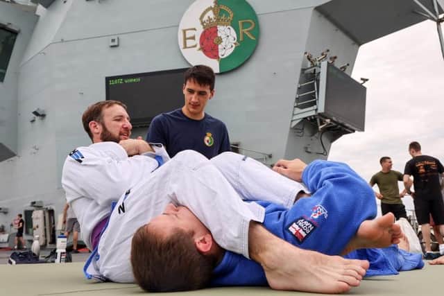 Sailors work on their ground-based skills as one is placed in an arm bar submission hold on HMS Queen Elizabeth. Photo: Royal Navy/Twitter