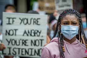 A demonstrator outside Portsmouth Guildhall listens to a speaker as she stands in front of a poignant message.