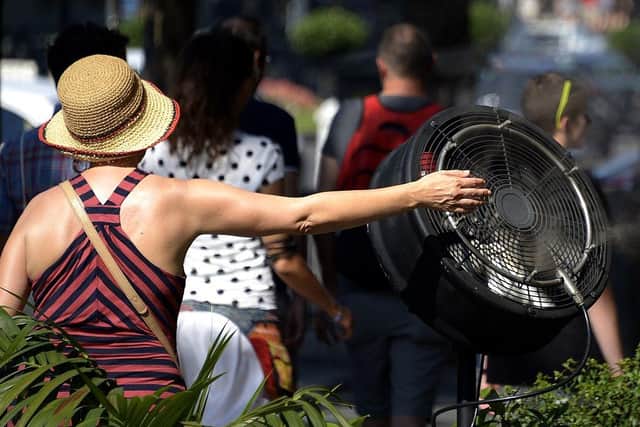 A woman cools off with a fan displayed on a terrace as UK temperatures continue to rise.