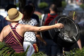 A woman cools off with a fan displayed on a terrace as UK temperatures continue to rise.