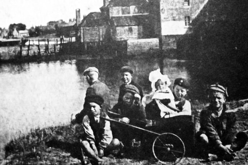 Beside Slipper Mill, Emsworth. With a baby wrapped up against the chill Emsworth boys gather alongside Slipper Mill. Picture: Tony New.