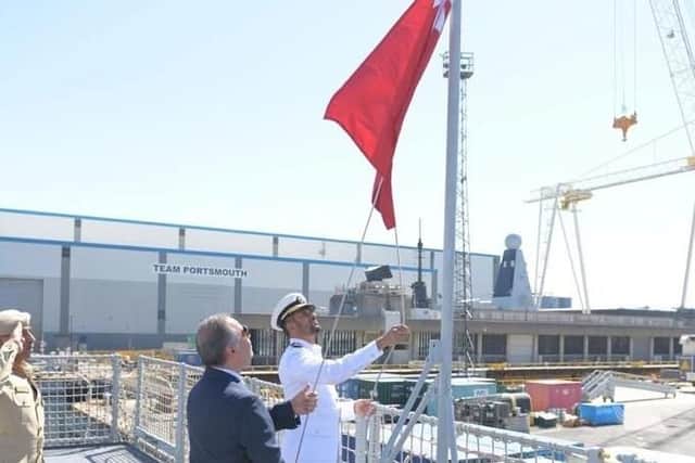 Bahrani military officials raise their nation's flag on the flight deck of the former HMS Clyde. Photo: Twitter/Bahrain Embassy UK