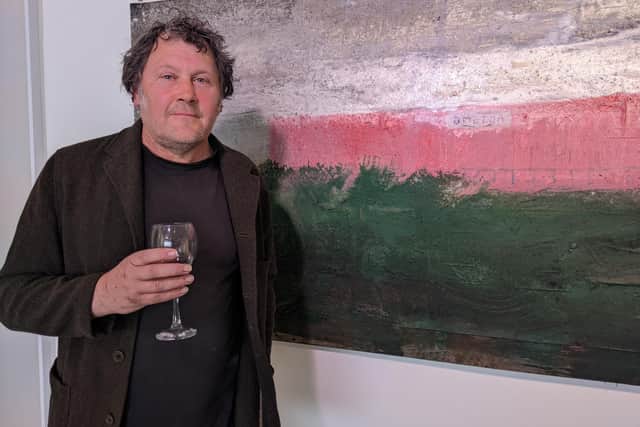 Andrew Hardwick next to one of his paintings at the exhibition. 