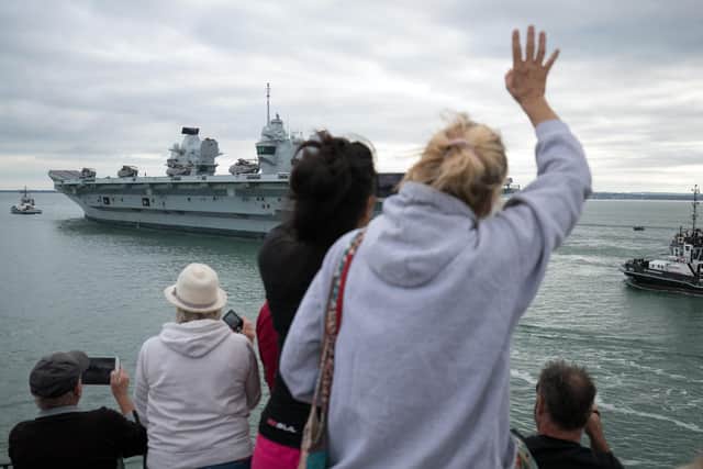 People wave from the Round Tower as the Royal Navy aircraft carrier HMS Queen Elizabeth leaves Portsmouth Naval Base as it sets sail for flight trials. Picture: Andrew Matthews/PA