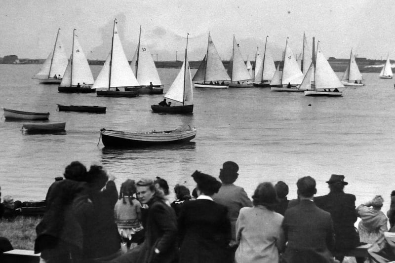 A regatta in Eastney’s Lock Lake. Spectators in front of the Thatched House pub at Milton Locks enjoy a regatta of sloop rigged dinghies.