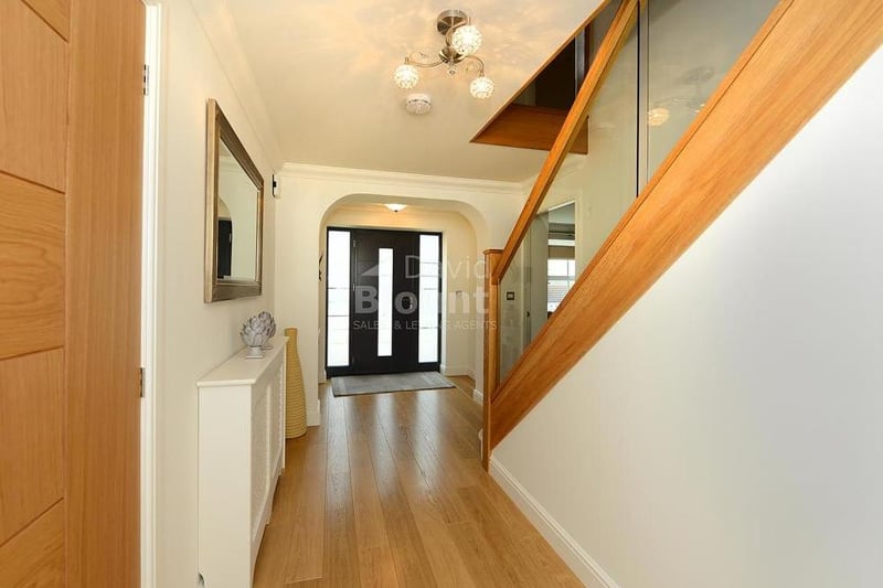 You are greeted by this entrance hall when you step through the front door. It features wooden veneer flooring and a glass balustrade staircase.