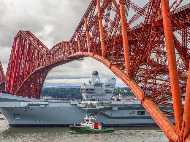 HMS Queen Elizabeth passes under the Forth Bridge as she heads back to sea following lengthy time at Rosyth for repairs and upgrades due to mechanical fault. July 22, 2024.