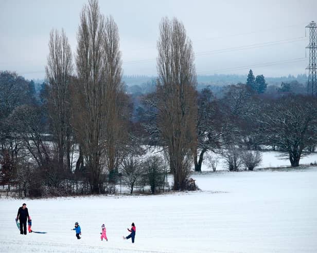 Family play on snow covered hill.