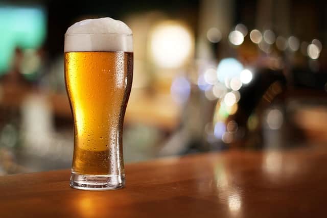 Glass of light beer on a dark pub.