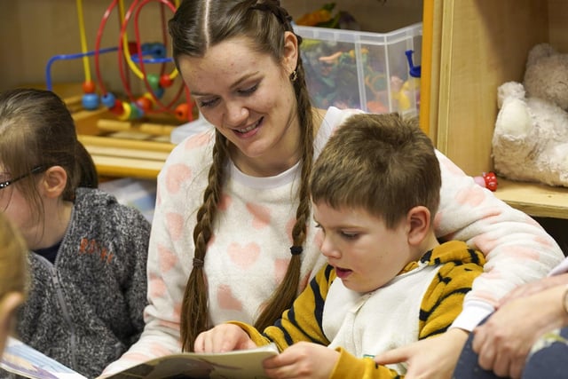 A teacher is reading a book with one of the pupils at St Thomas of Canterbury School.
