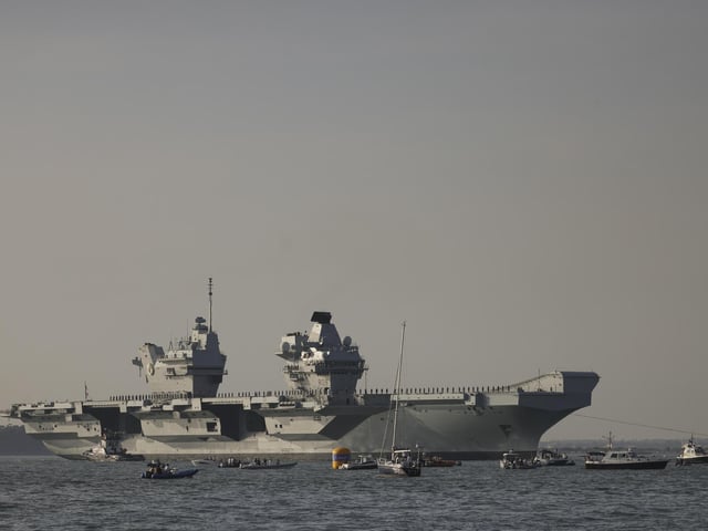 Pictured: HMS Queen Elizabeth enters the Solent off of Cowes and conducts a gun salute in front of the Royal Yacht Squadron.
