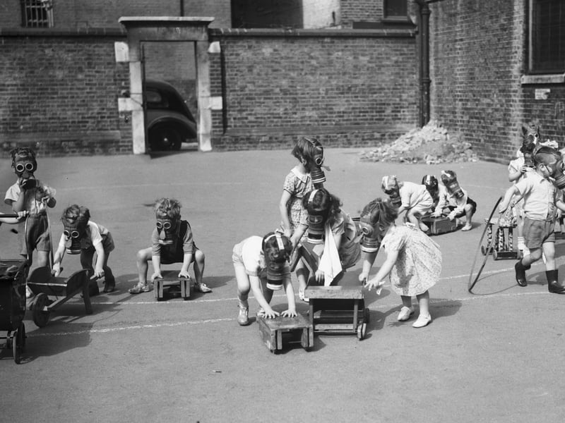 Children wearing their gas masks while playing in the playground (Photo by Keystone/Hulton Archive/Getty Images)