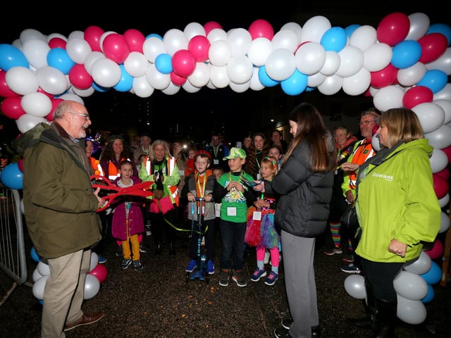 Chairman of the trustees of Rowans Hopsice, John Watkins, left, cuts a ribbon to mark the start of the walk. Starlit Walk in aid of Rowans Hospice, Portsmouth Historic Dockyard, HM Naval Base PortsmouthPicture: Chris Moorhouse (jpns 261023-22)