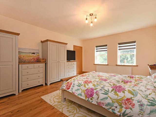 The master bedroom is a large room with oak flooring.
