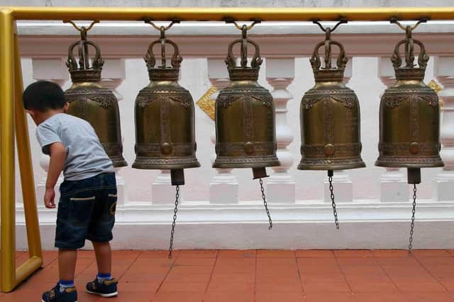 A boy rings temple bells at Wat Phra That Doi Suthep.