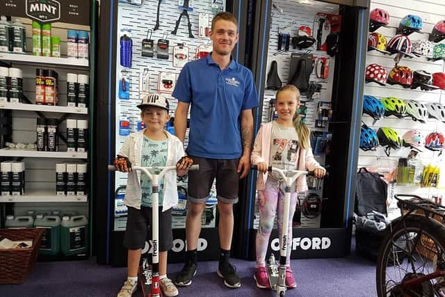 Toby, six, and his sister Phebe, nine, with a member of staff at Southsea Cycles on Friday. Picture: Karah Mew / Scooter Kids and the Portsmouth Park Adventures