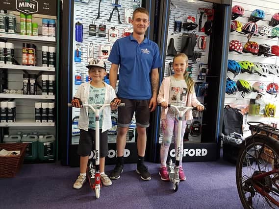 Toby, six, and his sister Phebe, nine, with a member of staff at Southsea Cycles on Friday. Picture: Karah Mew / Scooter Kids and the Portsmouth Park Adventures