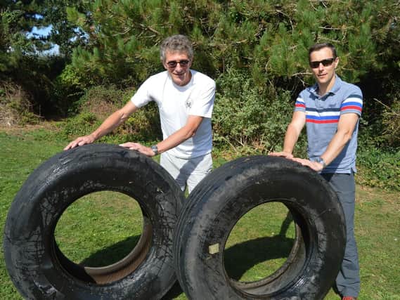 Cllr Kevin Casey, left, with local resident Brian Briggs and the tyres found in Stokes Bay. Picture: David George