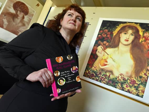 Historian and author of Pre Raphaelite Girl Gang Kirsty Stonell Walker. She stands next to a copy of Jane Morris by Dante Gabriel Rossetti.  The poster to her right is Venus Vertocordia also by Rossetti, this time featuring Alexa Wilding.
