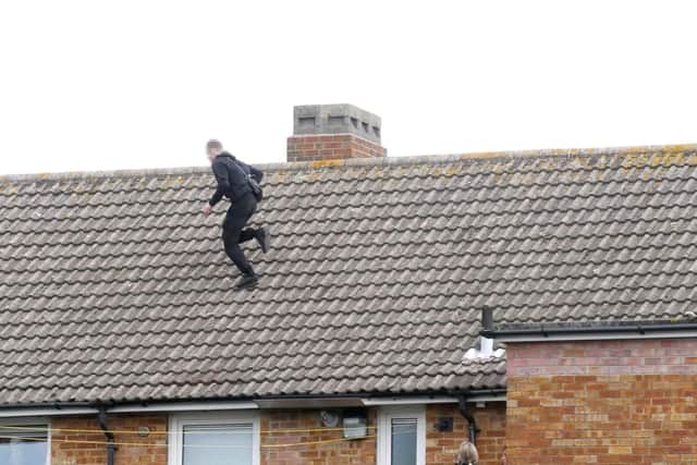 Police negotiators look as a man on a Portsmouth City Council block of flats in Murefield Road, Portsmouth, near Asda runs across the pitched roof. Picture: Habibur Rahman