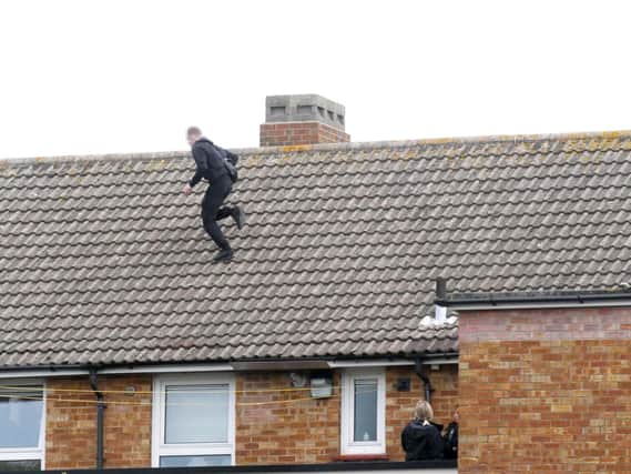 Police negotiators look as a man on a Portsmouth City Council block of flats in Murefield Road, Portsmouth, near Asda runs across the pitched roof. Picture: Habibur Rahman