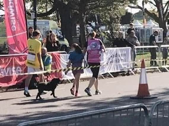 The girl holding the dog near the finish line. Picture: @TheAlastair2000/Twitter