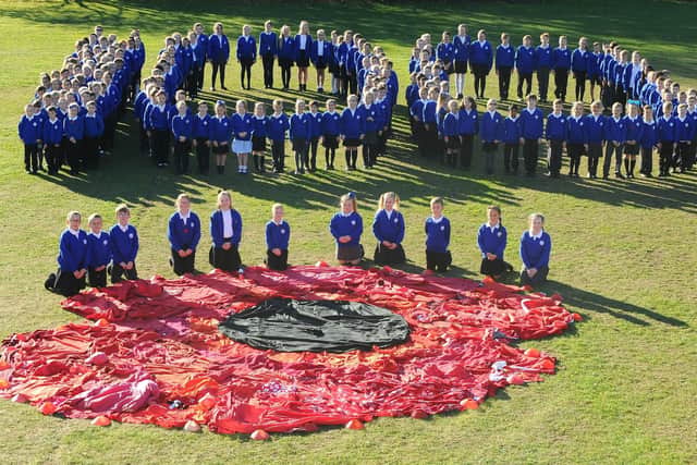The children of Padnell Junior School alongside the giant poppy they created