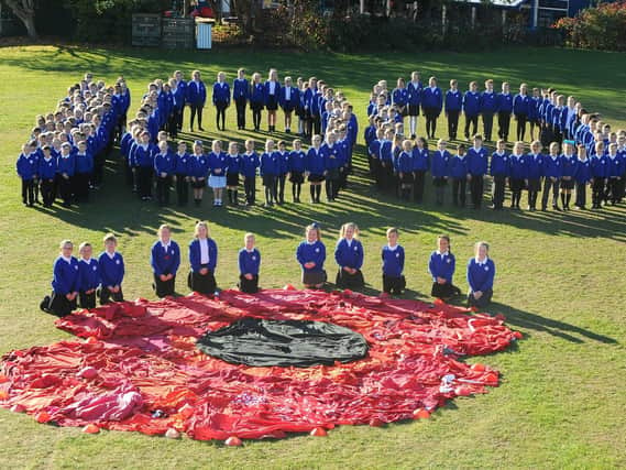 The children of Padnell Junior School alongside the giant poppy they created