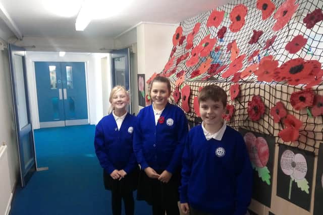 (L to R) Erin Jones, 11, Holly Young, 11, and Harry Martin, 10, alongside examples of their work on the Poppy Corridor.