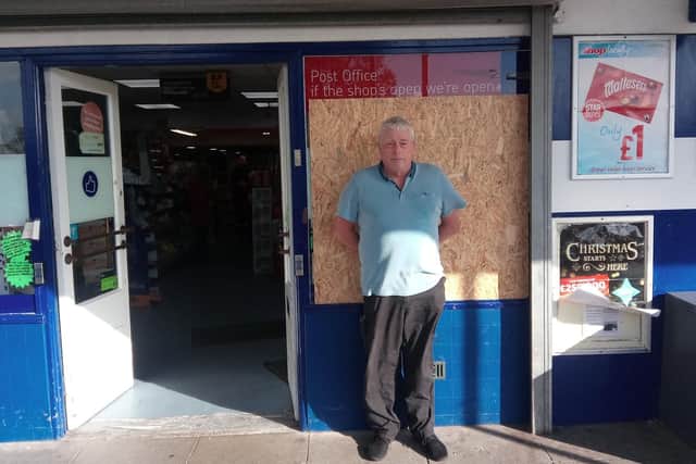 Kevin Jones alongside the boarded up windows where the glass panes were smashed.