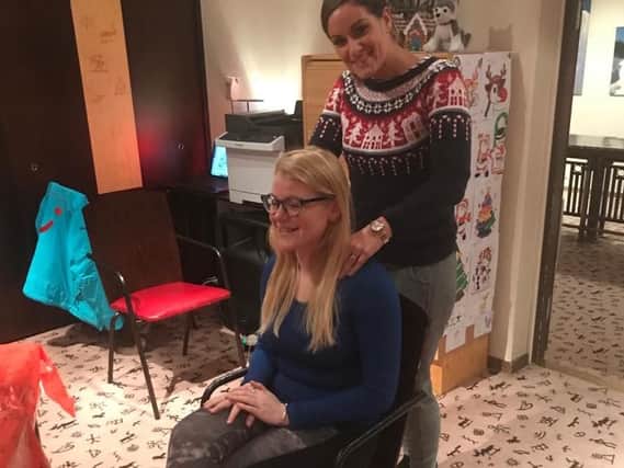 Helen Richards massages a fellow passenger while waiting for their flight back to the UK