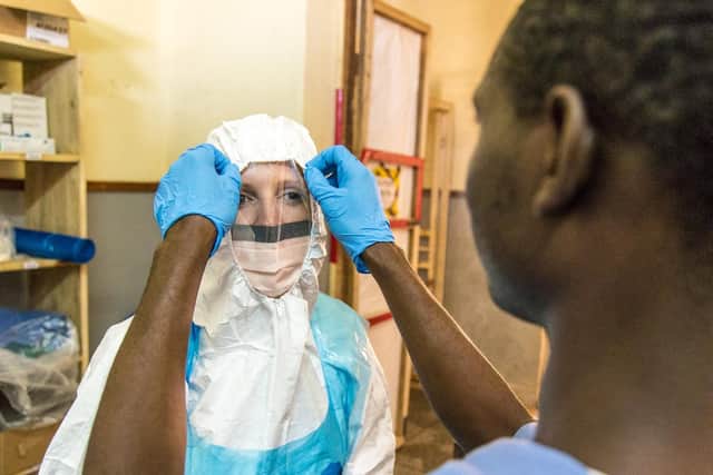 A colleague helps Ebola nurse Natalie Mounter into her protective clothing in Sierra Leone