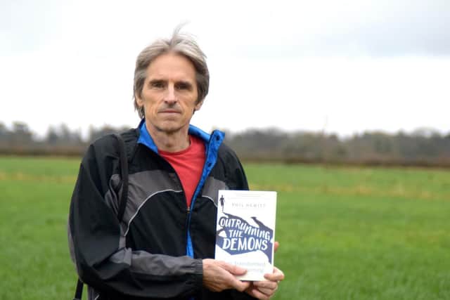 Runner Phil Hewitt with his book, Outrunning the Demons