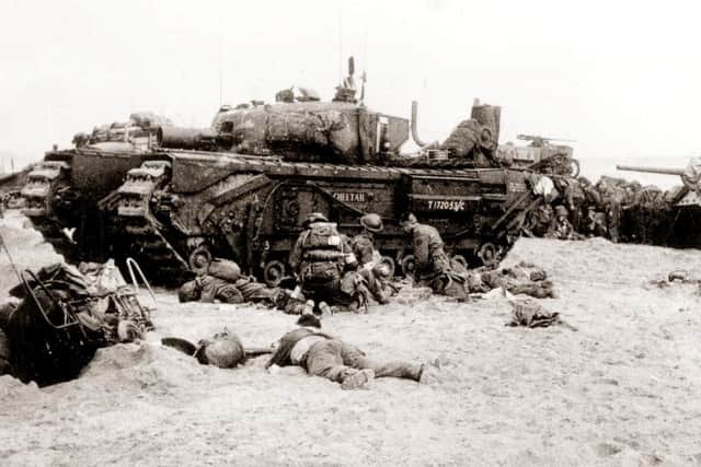 Soldiers taking cover behind a tank during the D-Day landings. Photo: PA